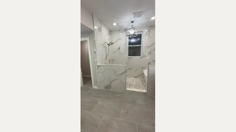 Bathroom with tiled shower pony walls, mosaic floor, and bathtub edge