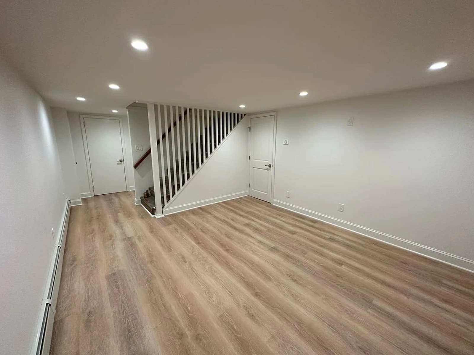 Light wood-look plank flooring through open room with staircase and recessed lights