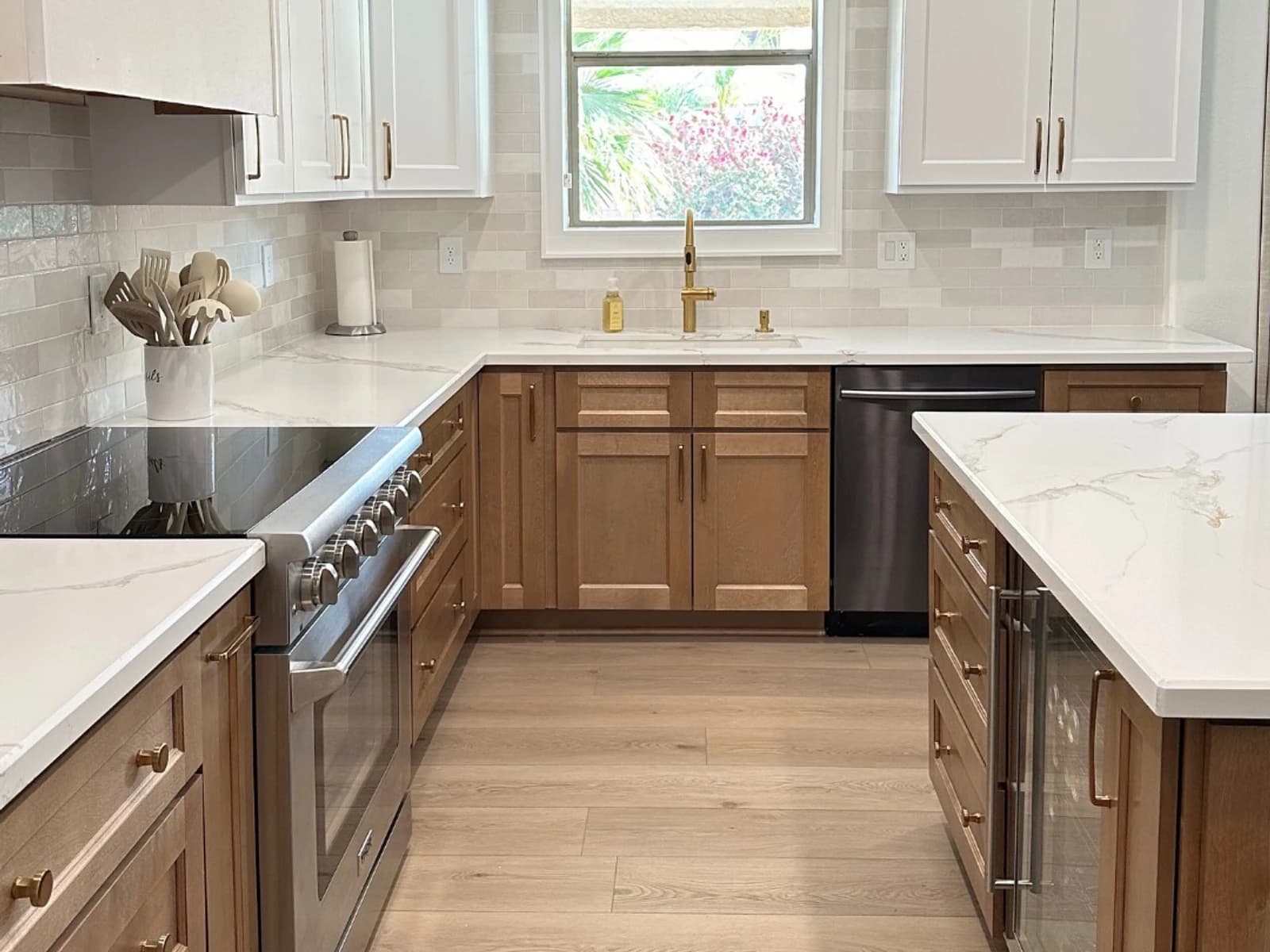 Finished kitchen remodel with wood lower cabinets, white upper cabinets, marble-look counters, tile backsplash, island, and plank flooring