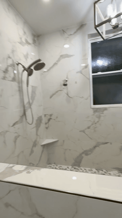 Bright custom tile shower with marble-look wall panels and updated fixtures