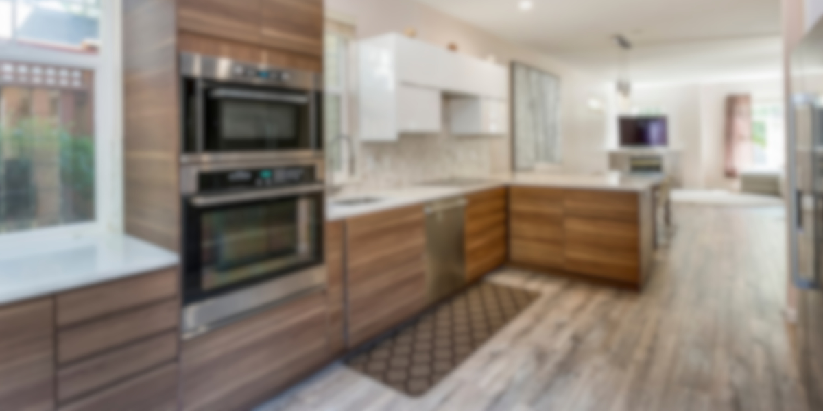 Modern kitchen renovation with wooden cabinets, stainless steel double oven, and spacious layout with natural light.